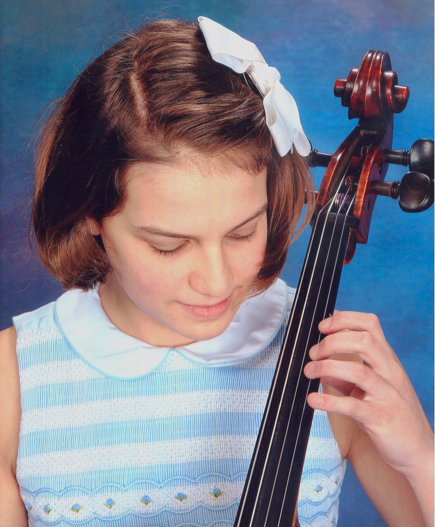 A youth playing a cello in front of a blue background