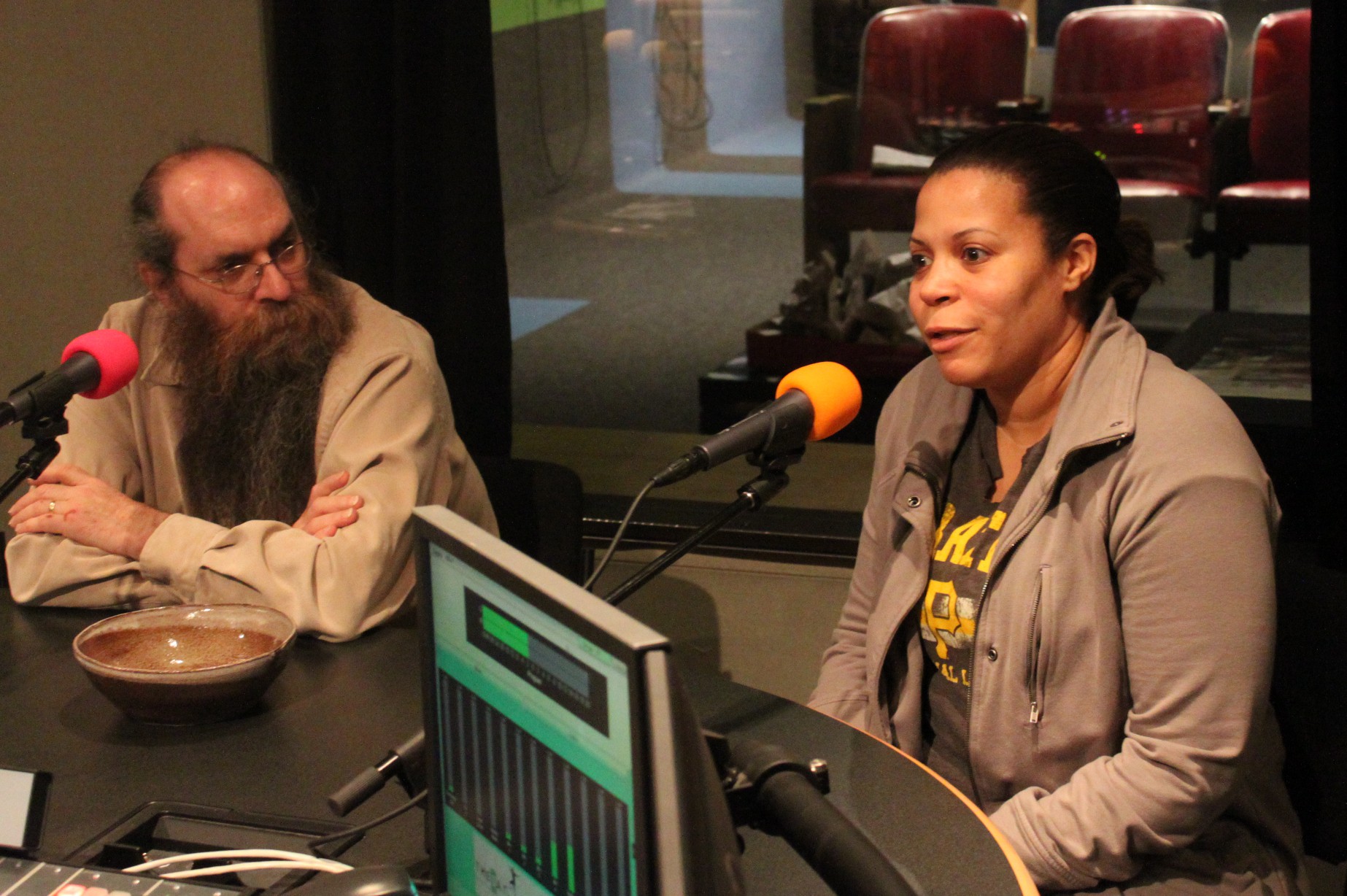 Two adults speaking into microphones being interviewed in a radio studio
