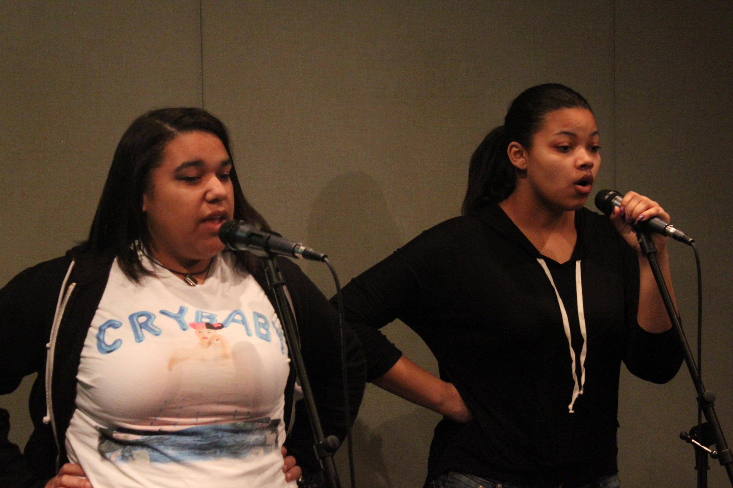 Two teens singing into microphones in a radio studio