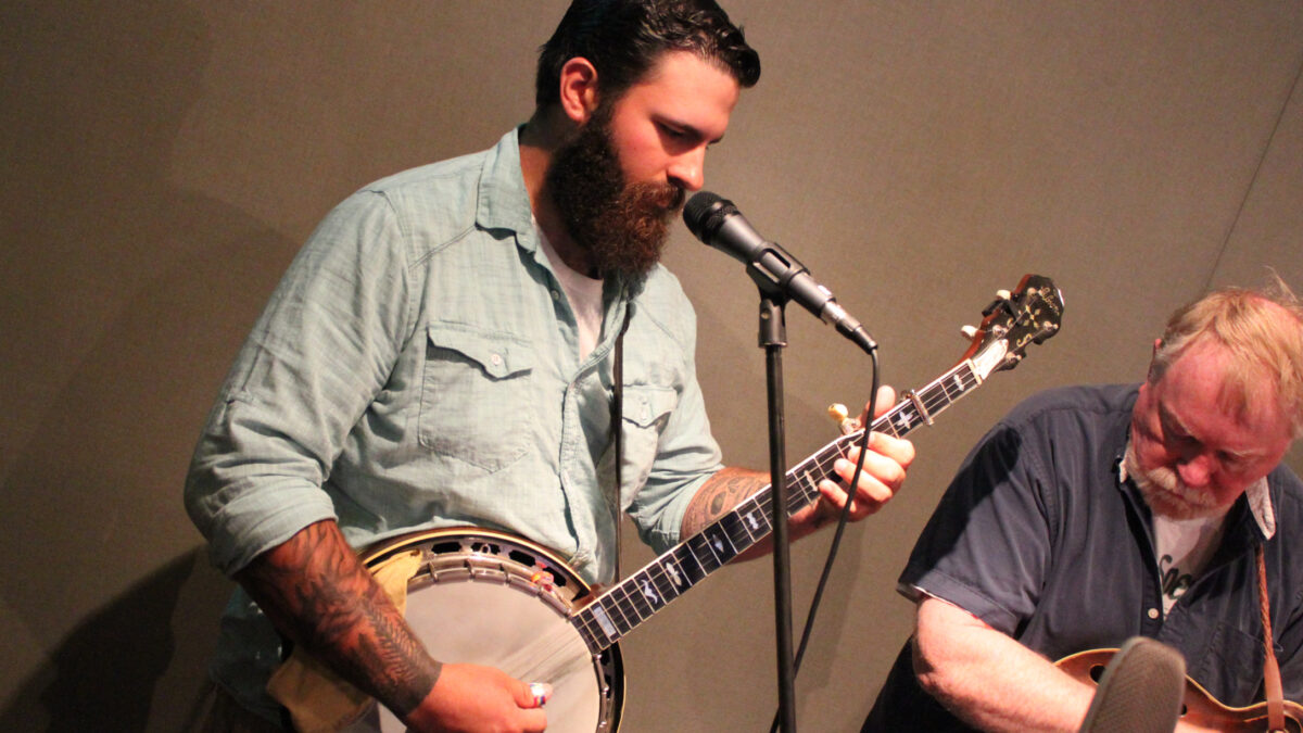 An adult playing banjo and an adult playing mandolin in a radio studio