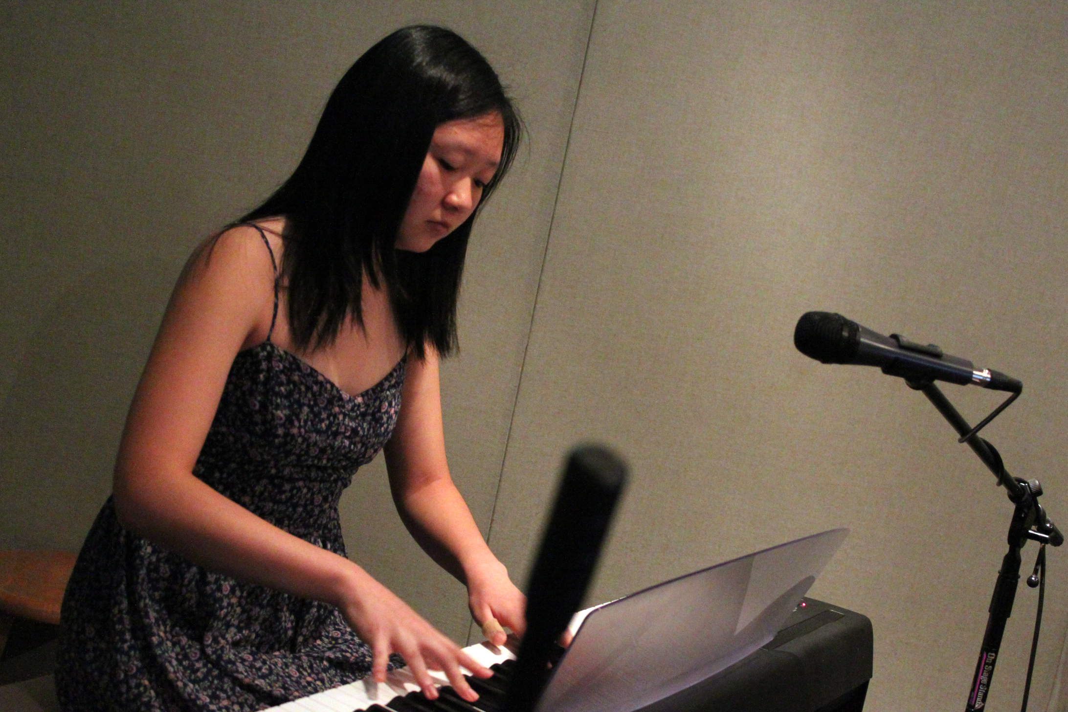 A teen playing a piano keyboard in a radio studio