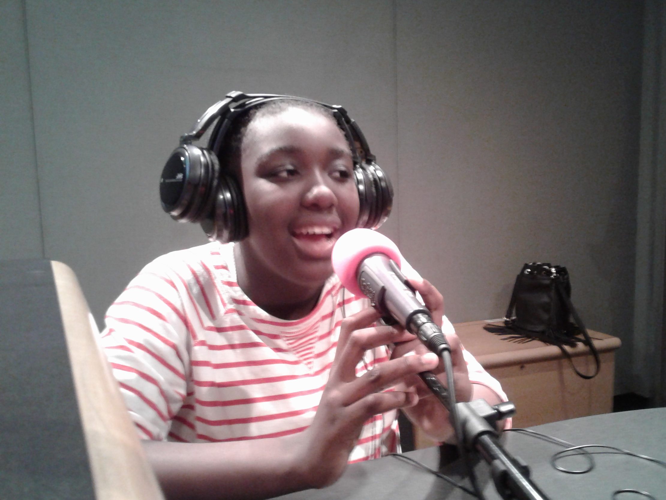 A youth wearing headphones speaking into a microphone in a radio studio