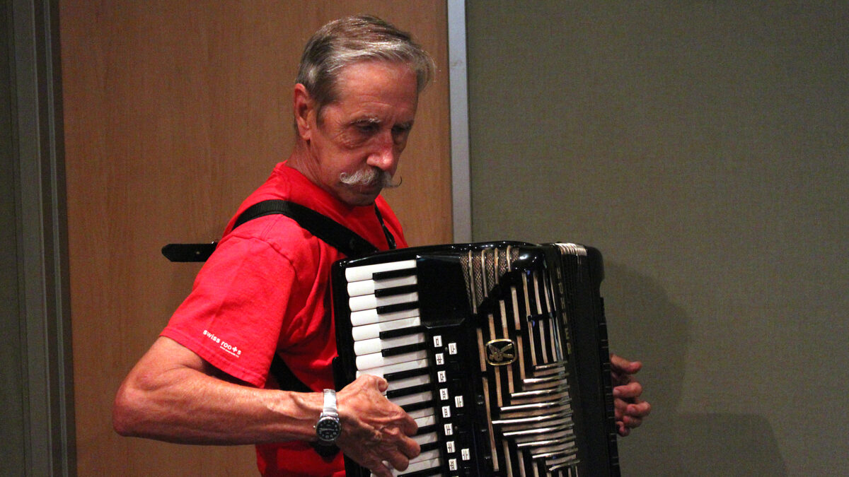 An adult playing an accordion in a radio studio