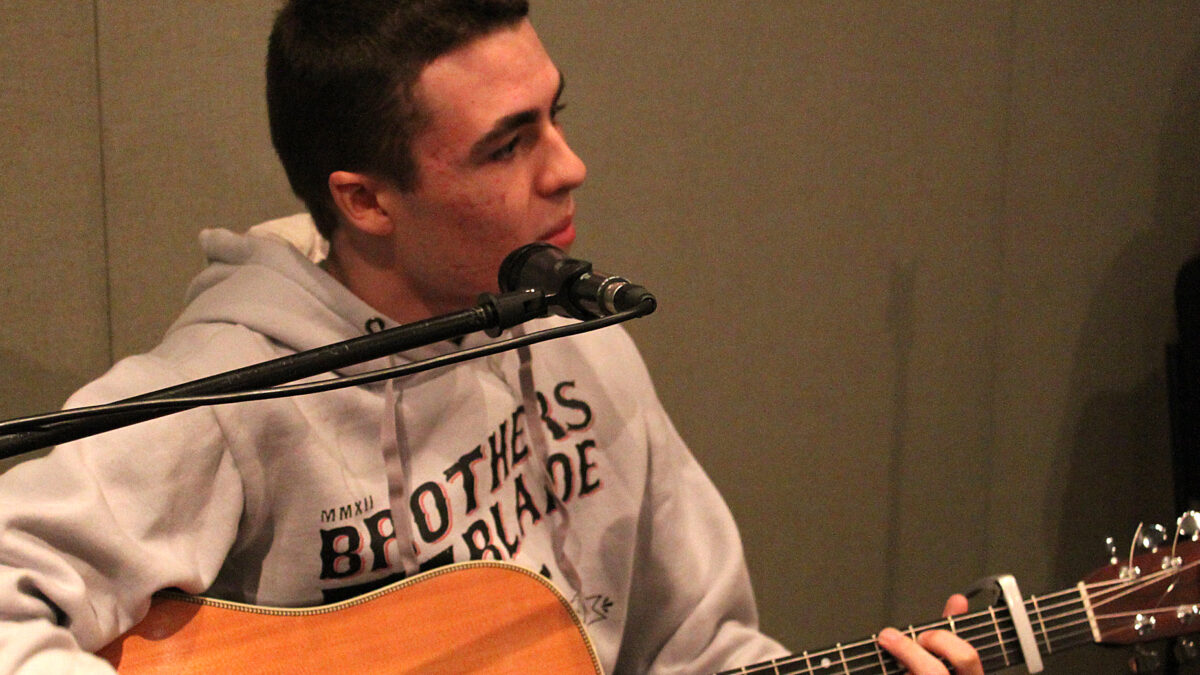 IMG_1979_PS A teen playing acoustic guitar and singing into a microphone in a radio studio