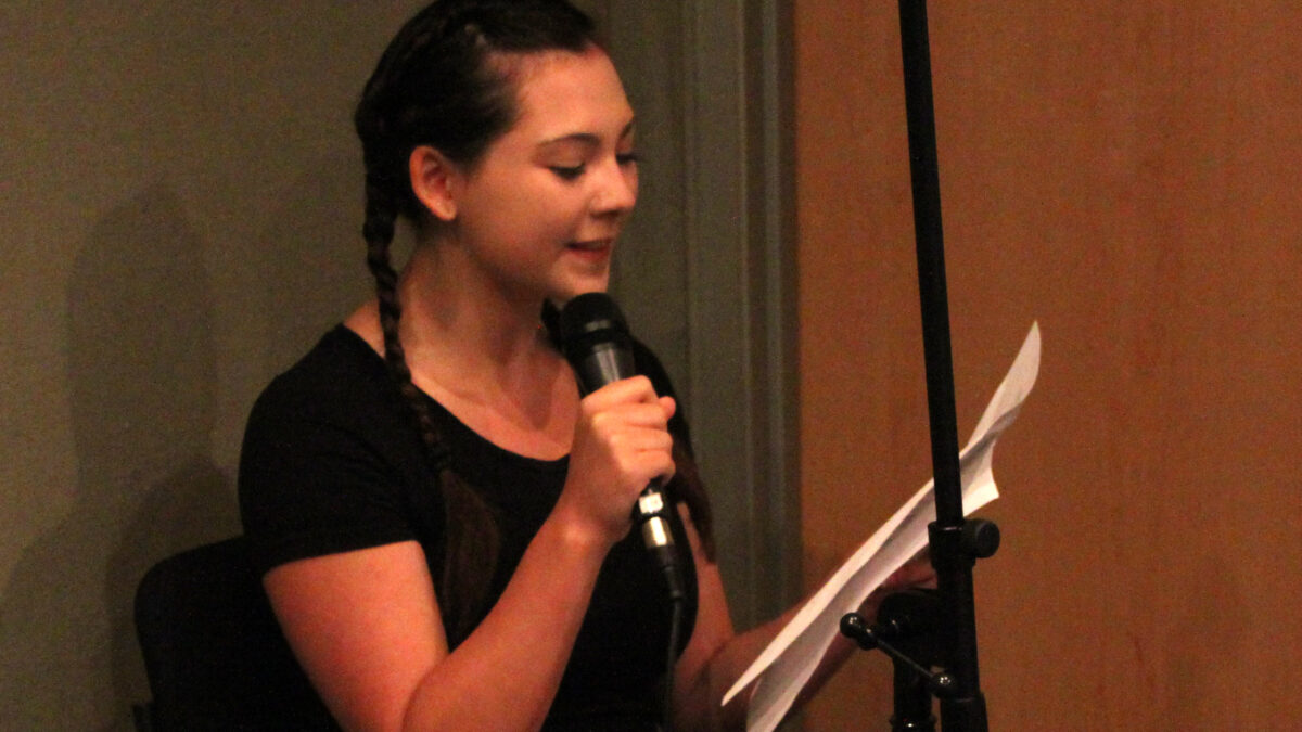 IMG_1980_PS A teen singing into a microphone holding a piece of paper in a radio studio