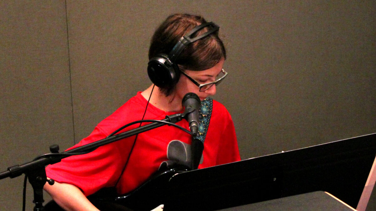 img_2042_web A teen wearing headphones playing an electric guitar in a radio studio