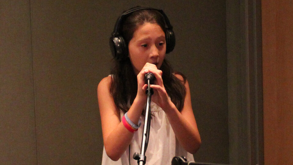 img_2045_web A youth wearing headphones singing into a microphone in a radio studio