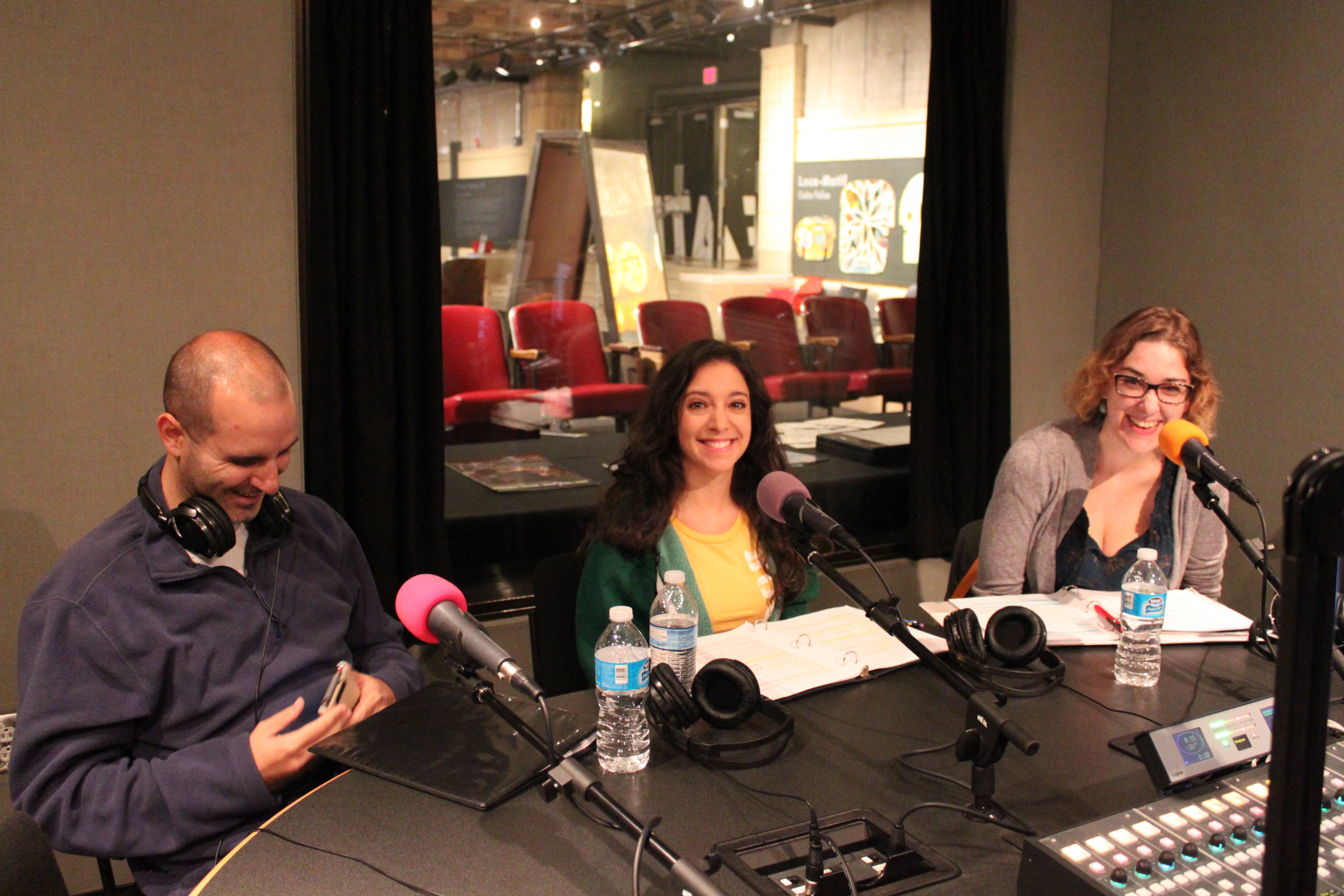 Three adults speaking into microphones in a radio studio
