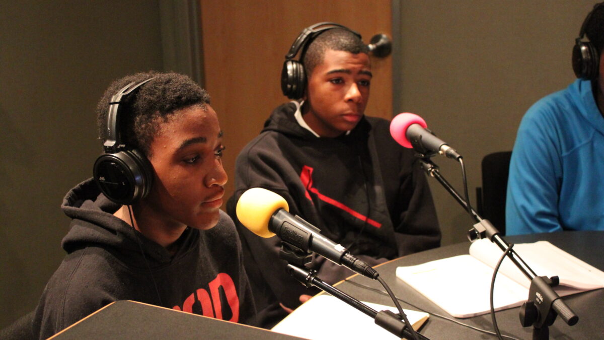 img_2091 Two youth wearing headphones sitting behind microphones in a radio studio