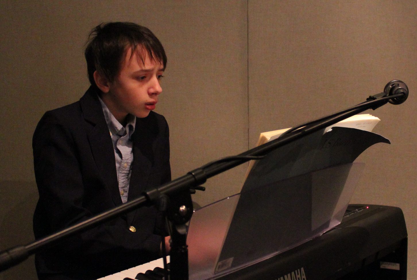 A teen playing a piano keyboard in a radio studio