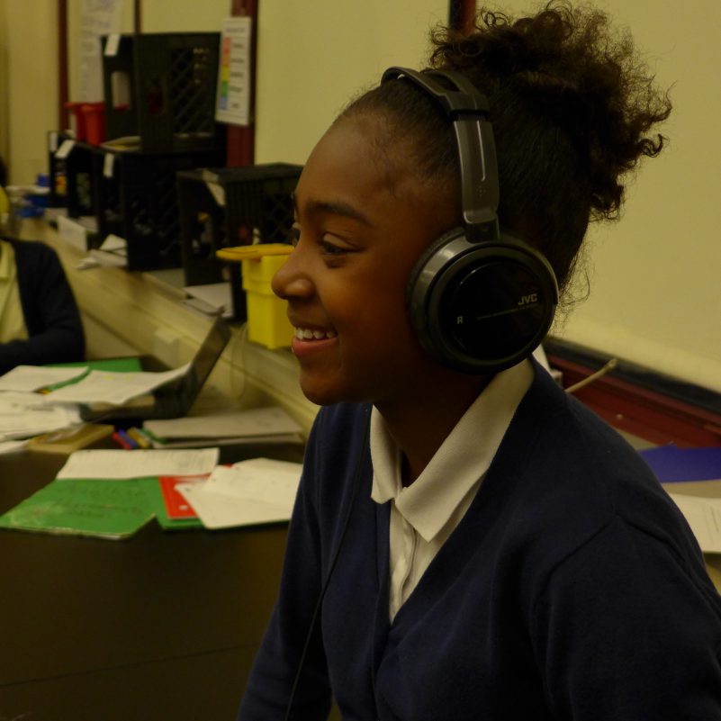 A youth wearing headphones smiling in a classroom
