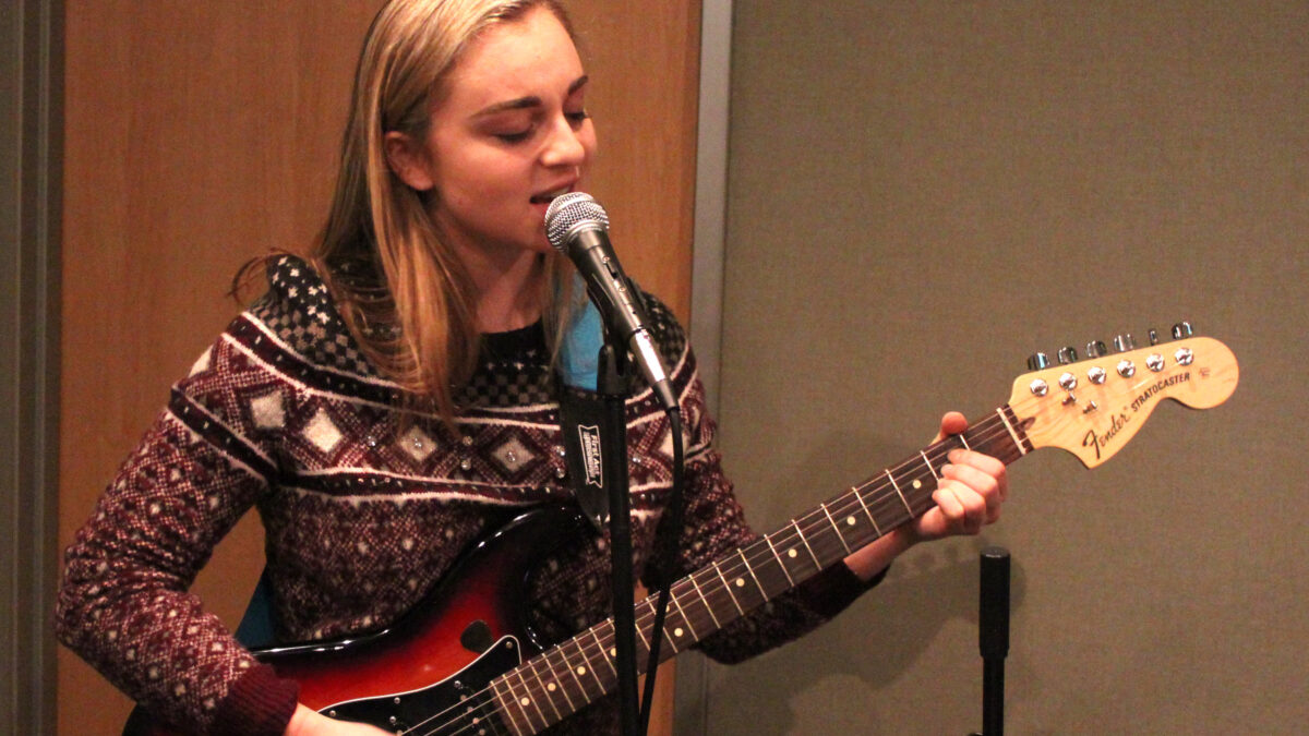 A teen playing electric guitar in a radio studio