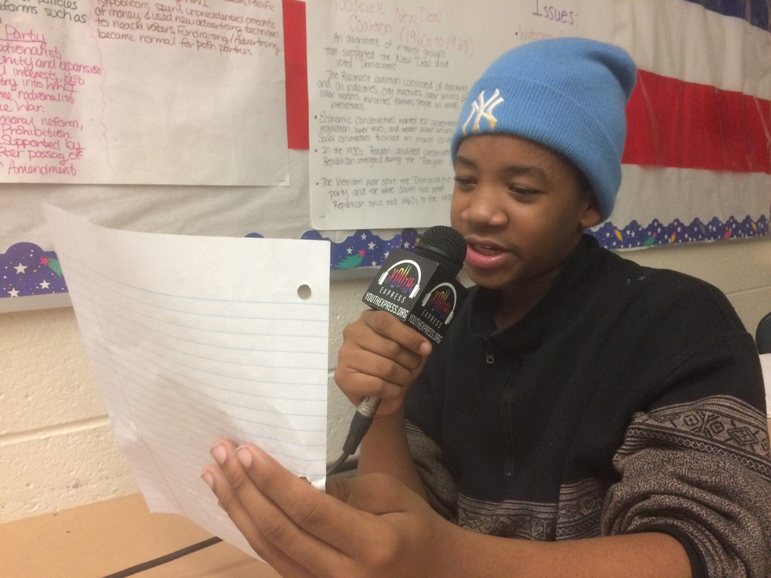A youth reading a piece of paper into a microphones