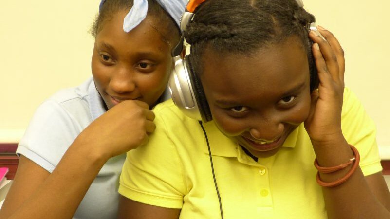 Two youth laughing, one wearing headphones