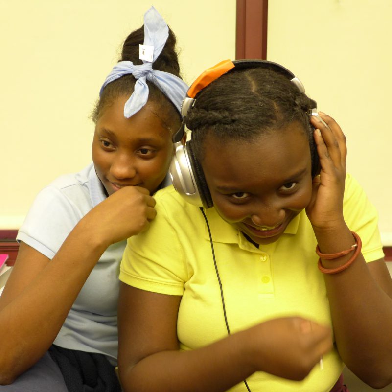 Two youth laughing, one wearing headphones
