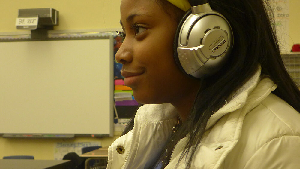 A youth wearing headphones sitting in a classroom