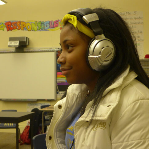 A youth wearing headphones sitting in a classroom