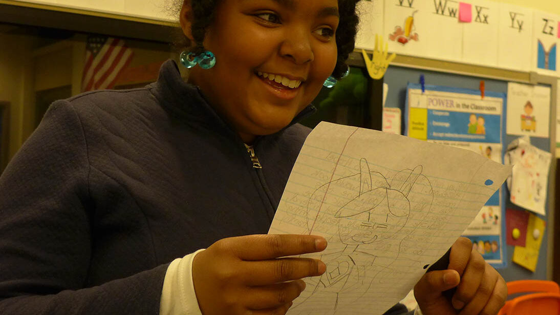 A youth holding and reading a piece of paper in a classroom