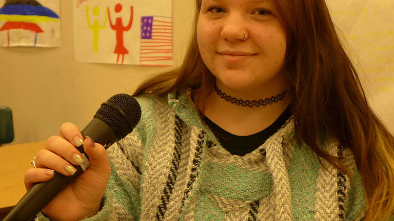 A teen holding a microphone in a classroom