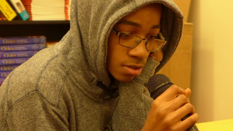 A teen holding a microphone in a classroom