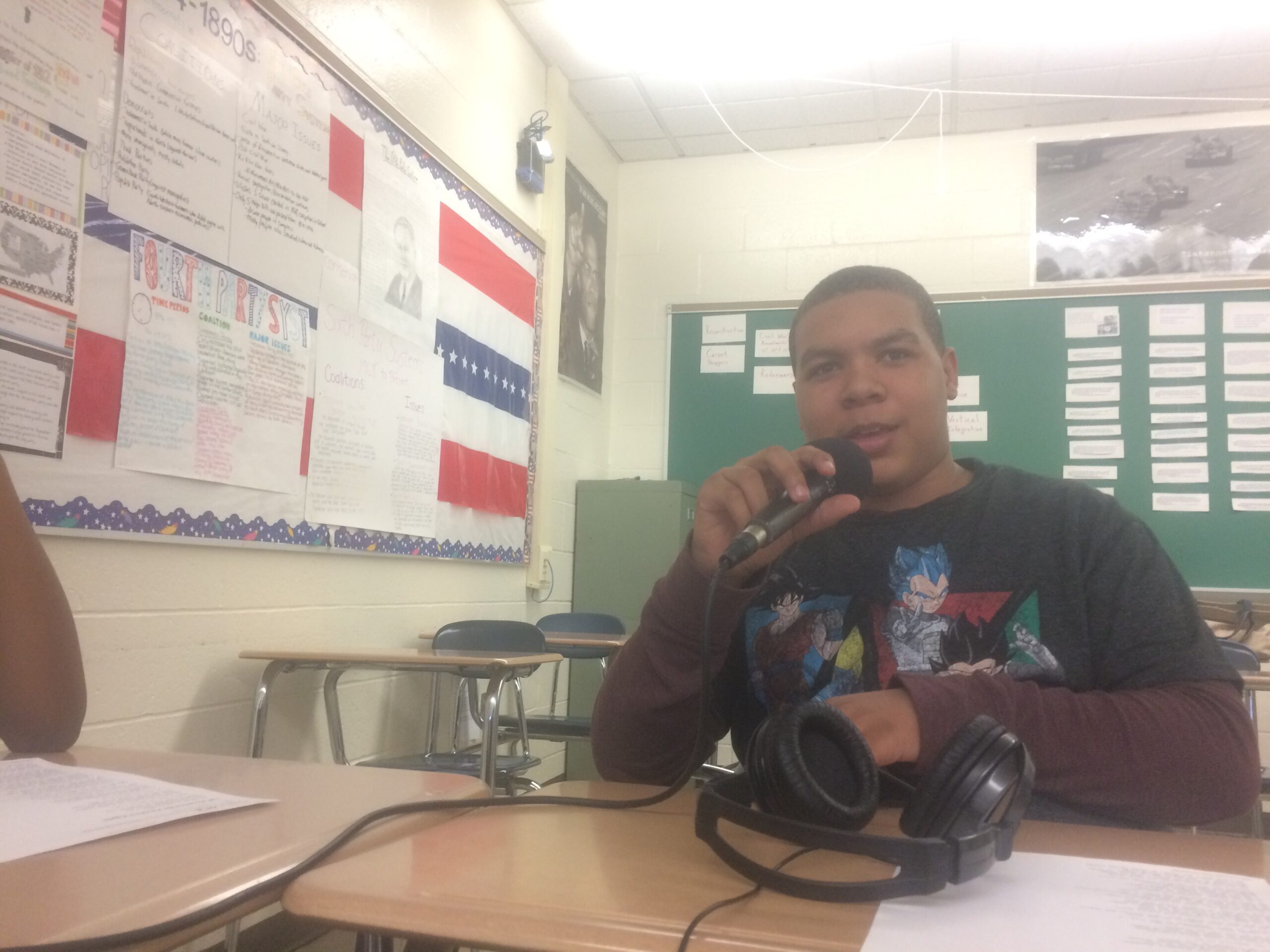 A youth speaking into a microphone in a classroom