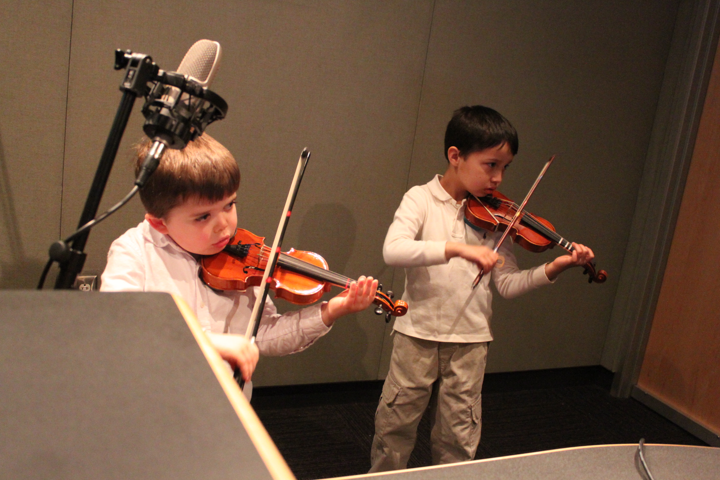 Two youth playing violins in a radio studio