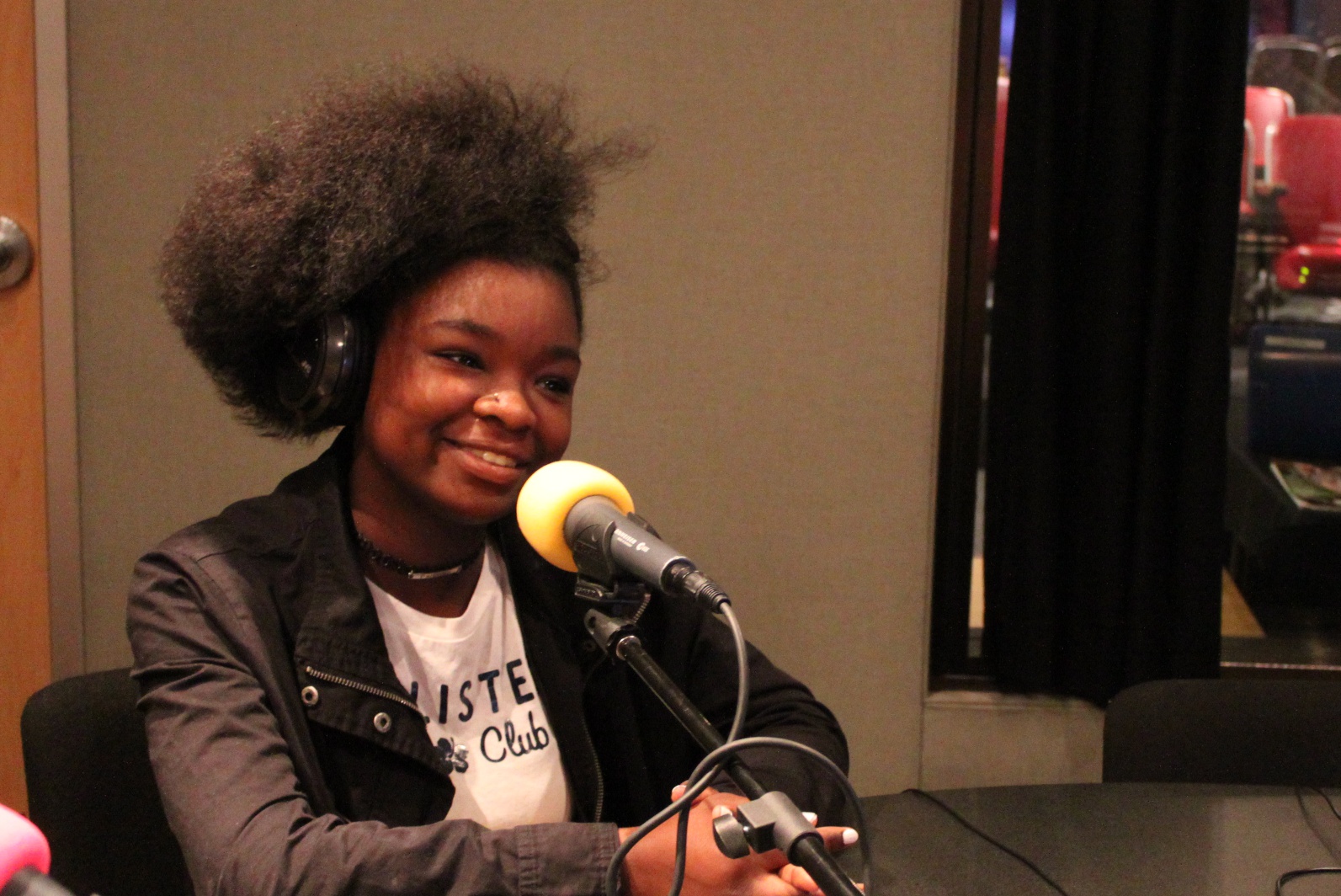 A youth wearing headphones smiling into a microphone in a radio studio