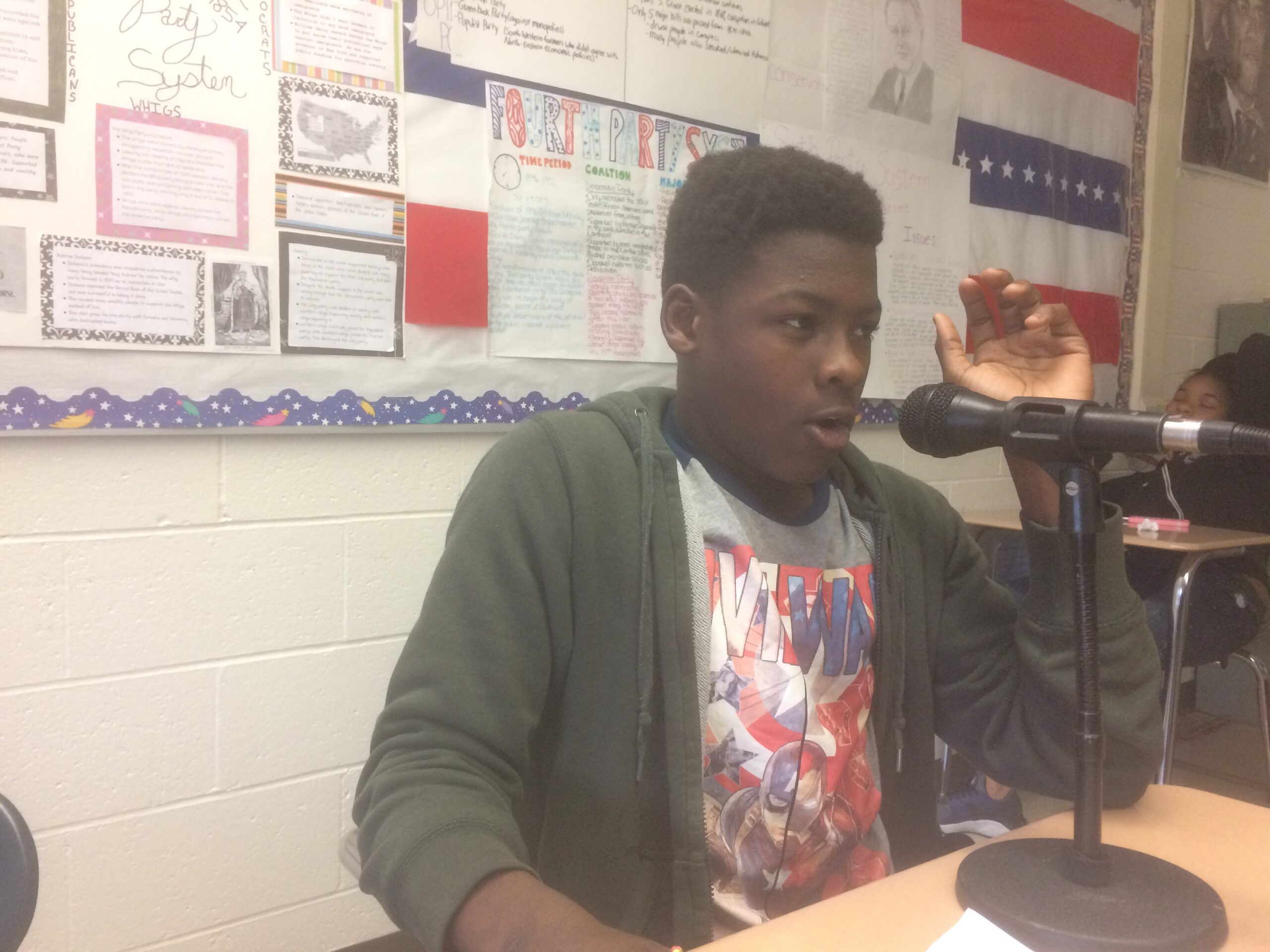 A youth speaking into a microphone in a classroom
