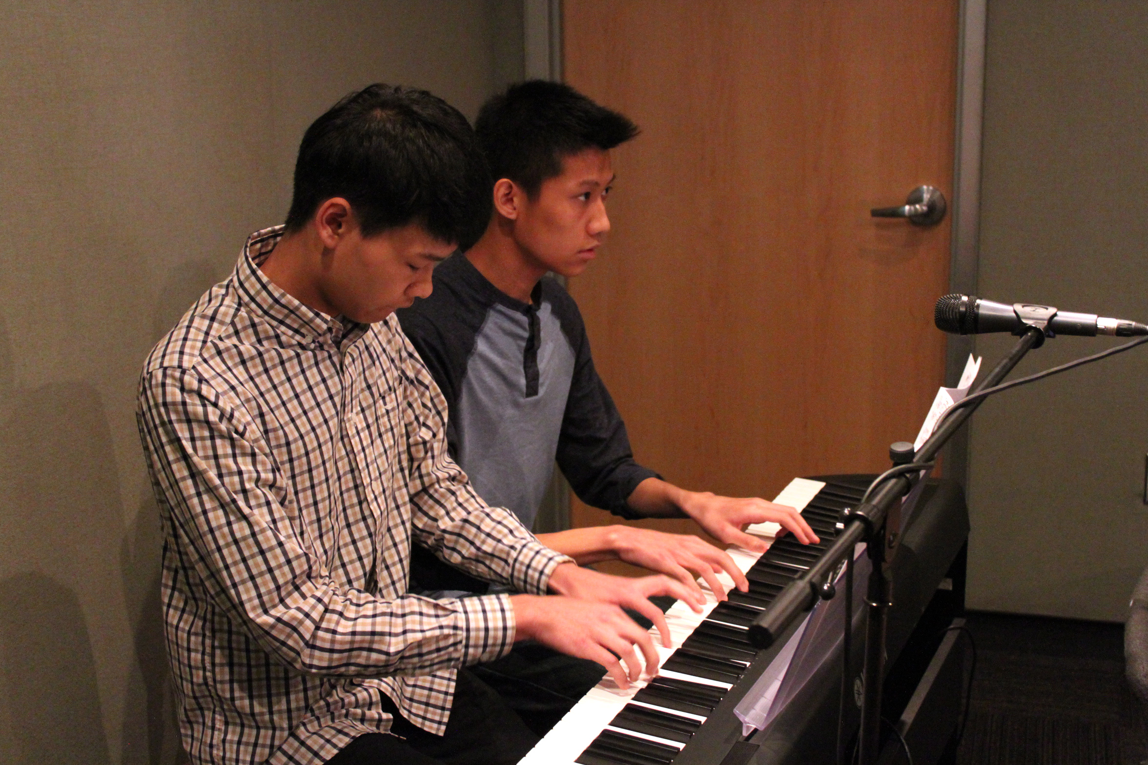 Two teens playing a piano keyboard in a radio studio