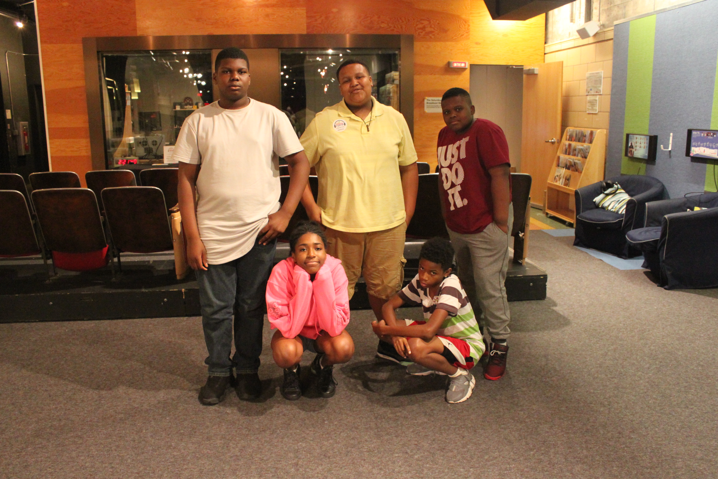 Five youth smiling and posing in front of a radio studio