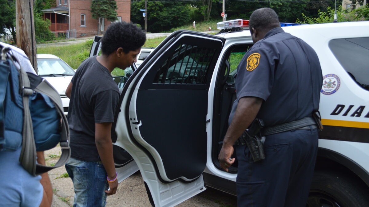 A police officer showing a youth the inside of a police car