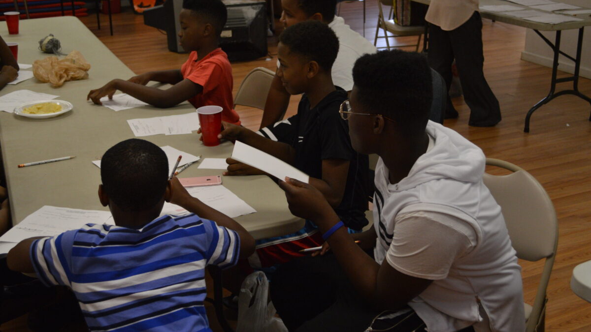Five youth sitting around a cafeteria table