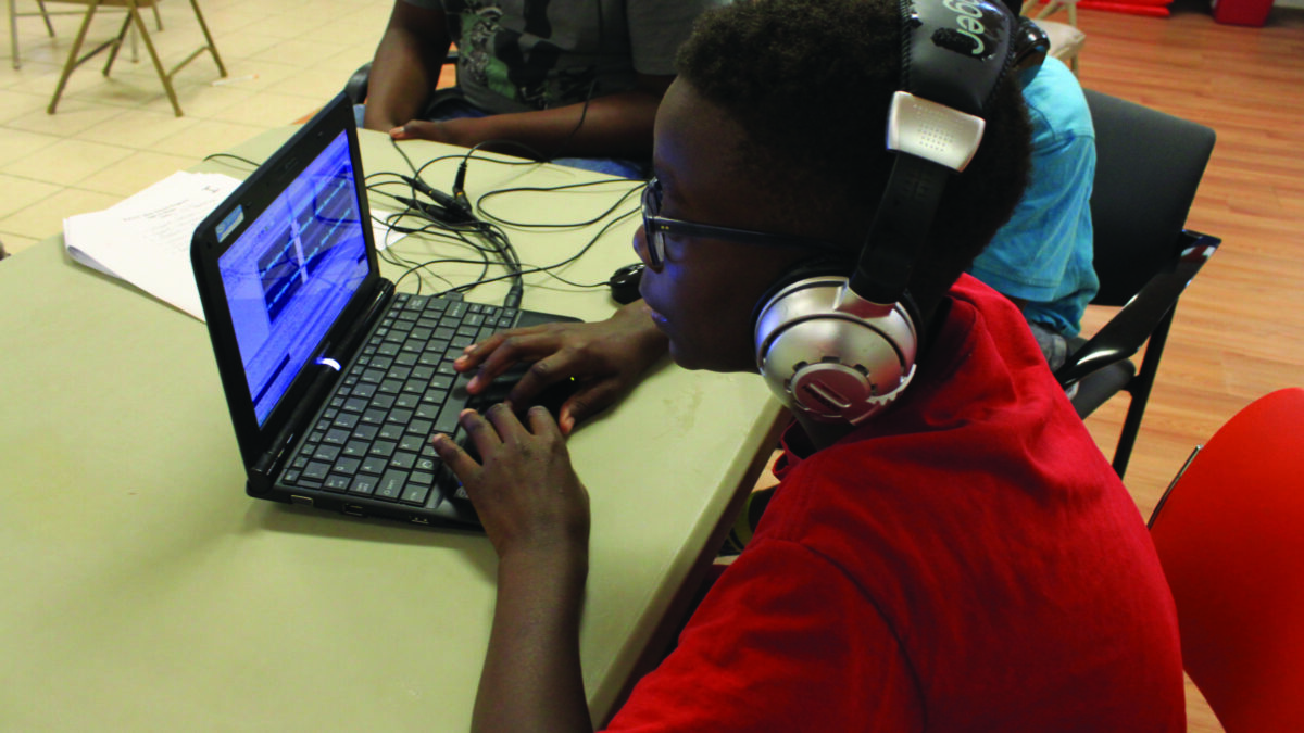 A youth wearing headphones looking at a laptop computer
