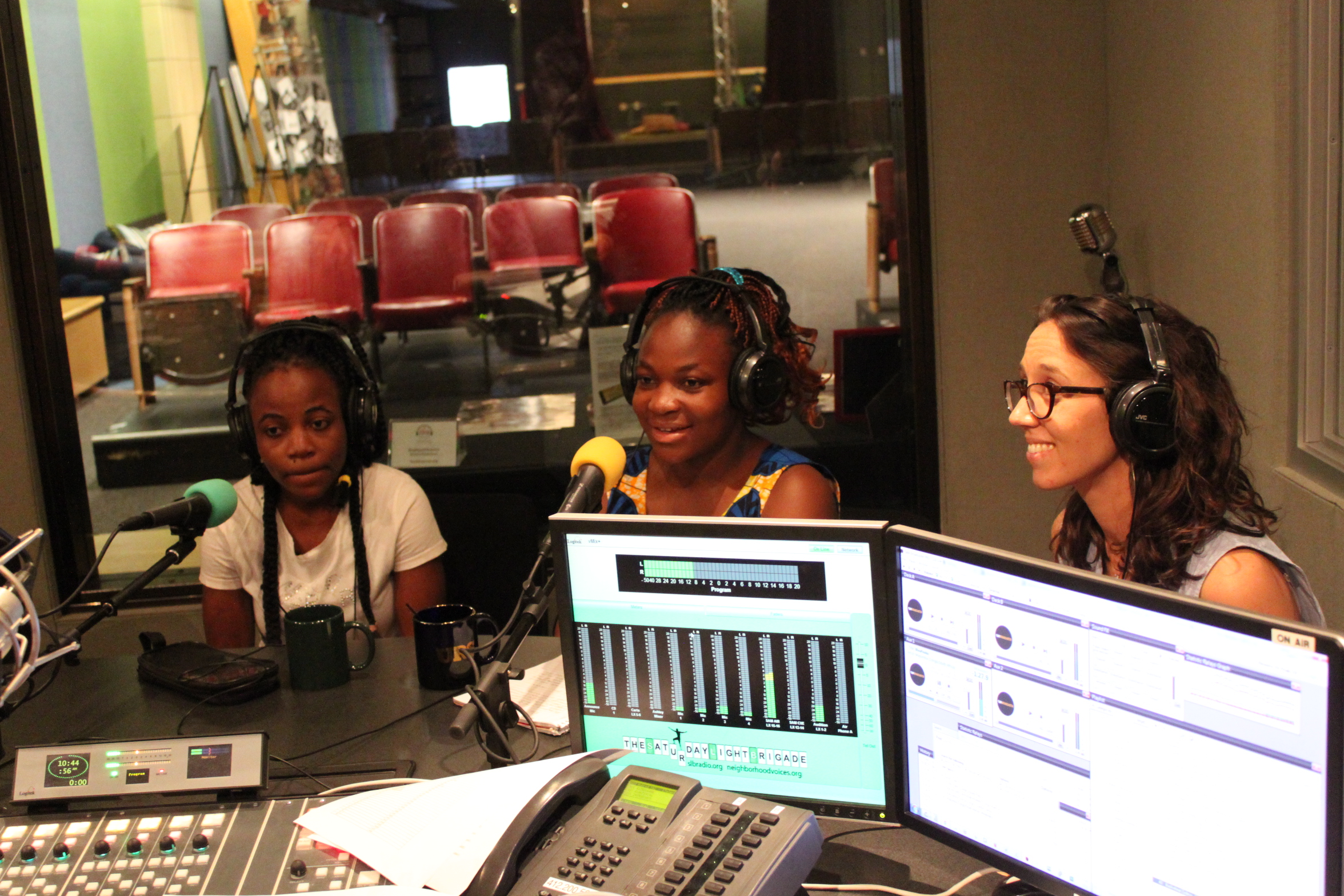 Three teens wearing headphones speaking into microphones in a radio studio