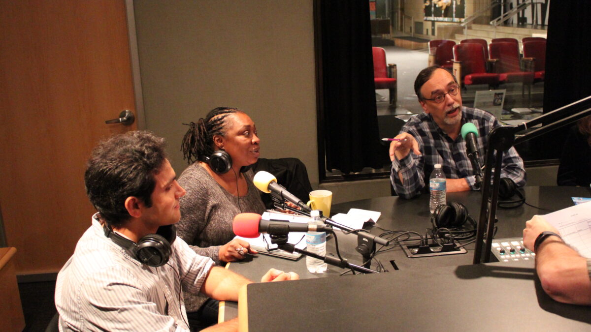 Three adults speaking into microphones in a radio studio