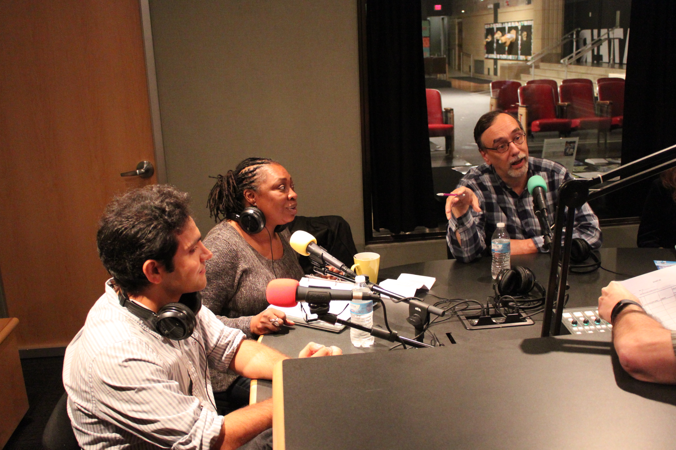 Three adults speaking into microphones in a radio studio