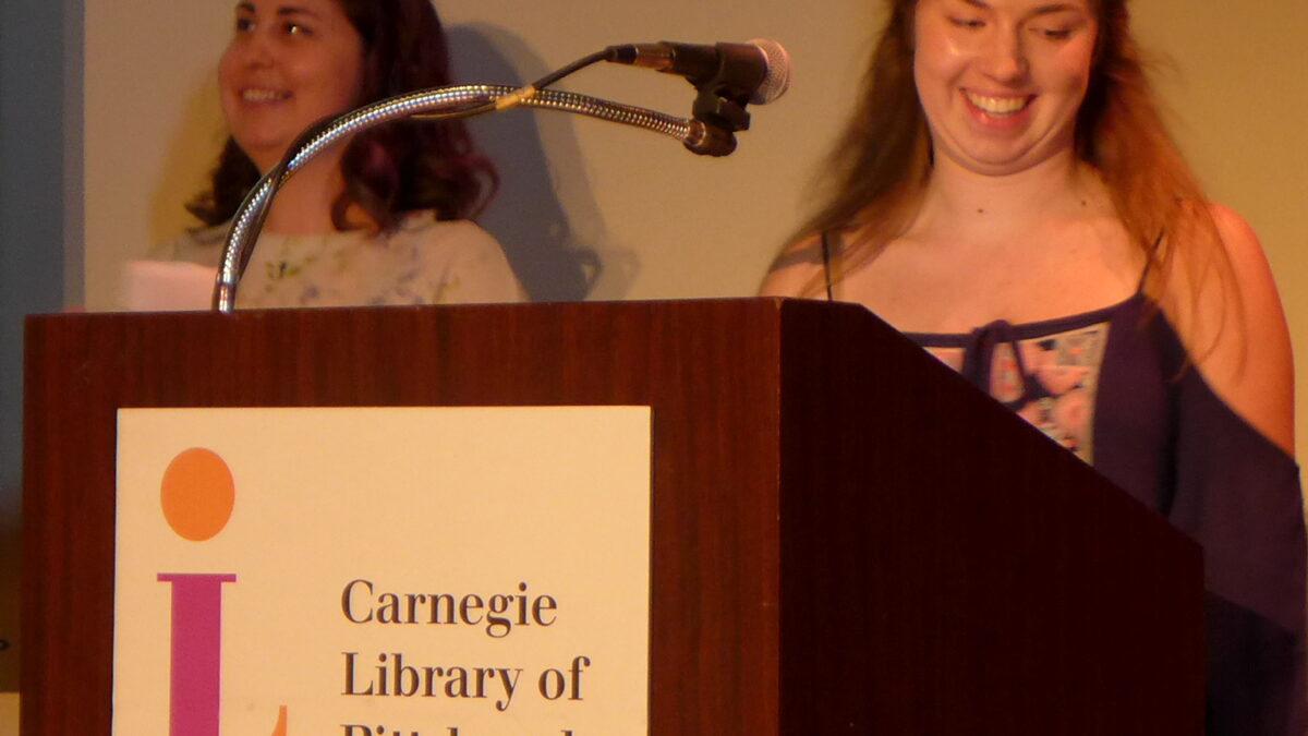 Two individuals smiling and standing behind a podium