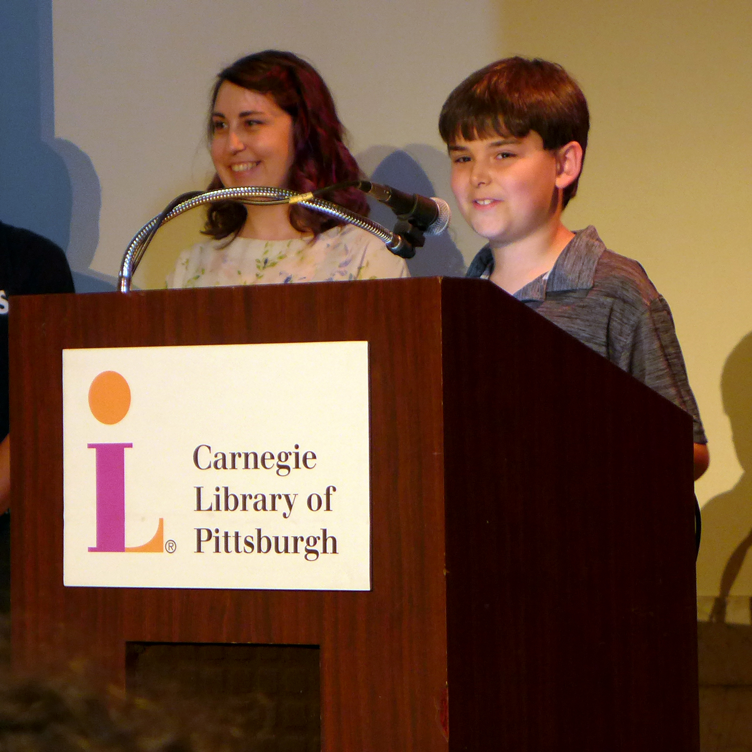 Two teens smiling and standing behind a podium