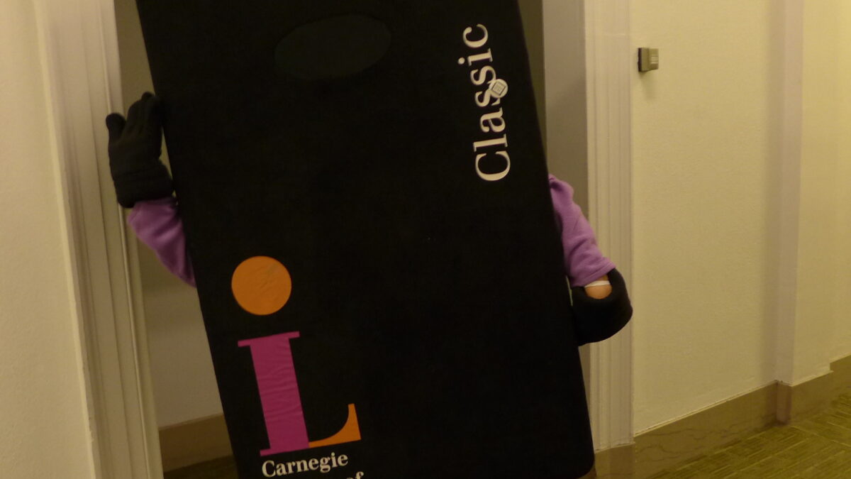 An individual holding up a black placard with the text "Classic Card" in white along the right side, and the Carnegie Library of Pittsburgh logo