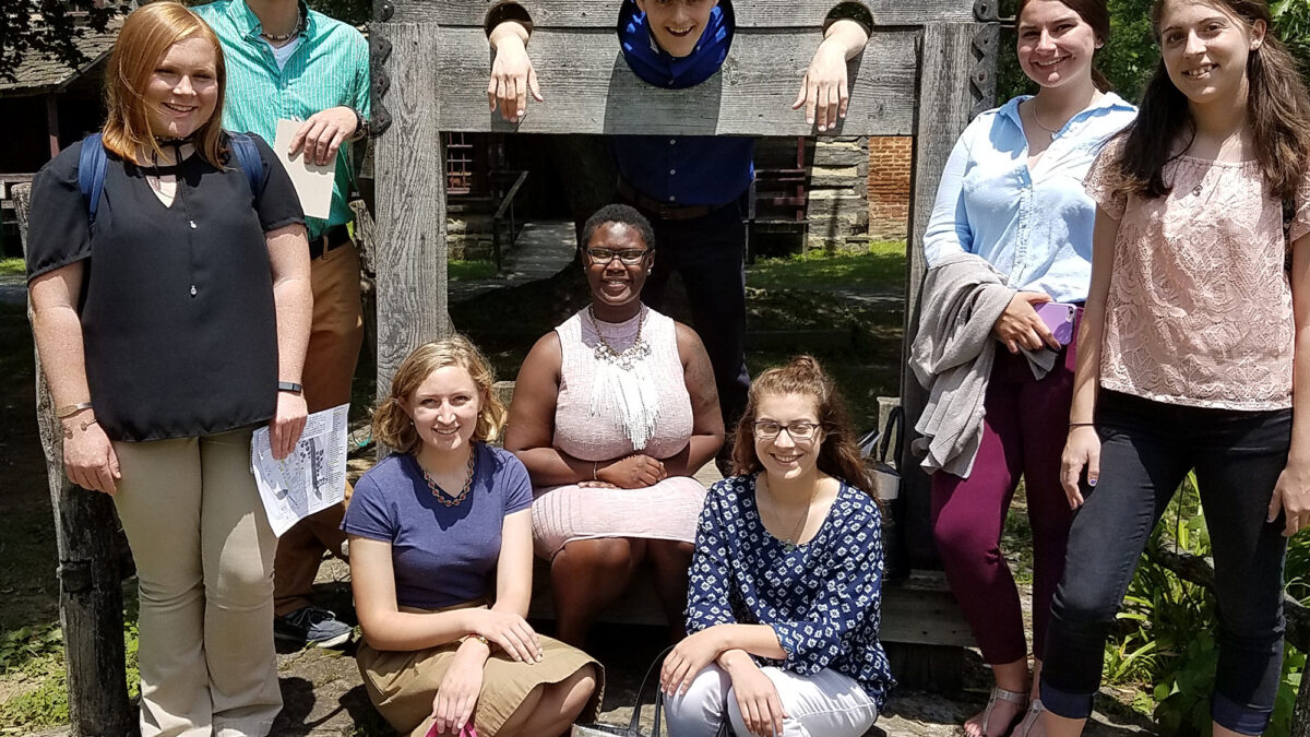 Eight teens posing around wooden stocks