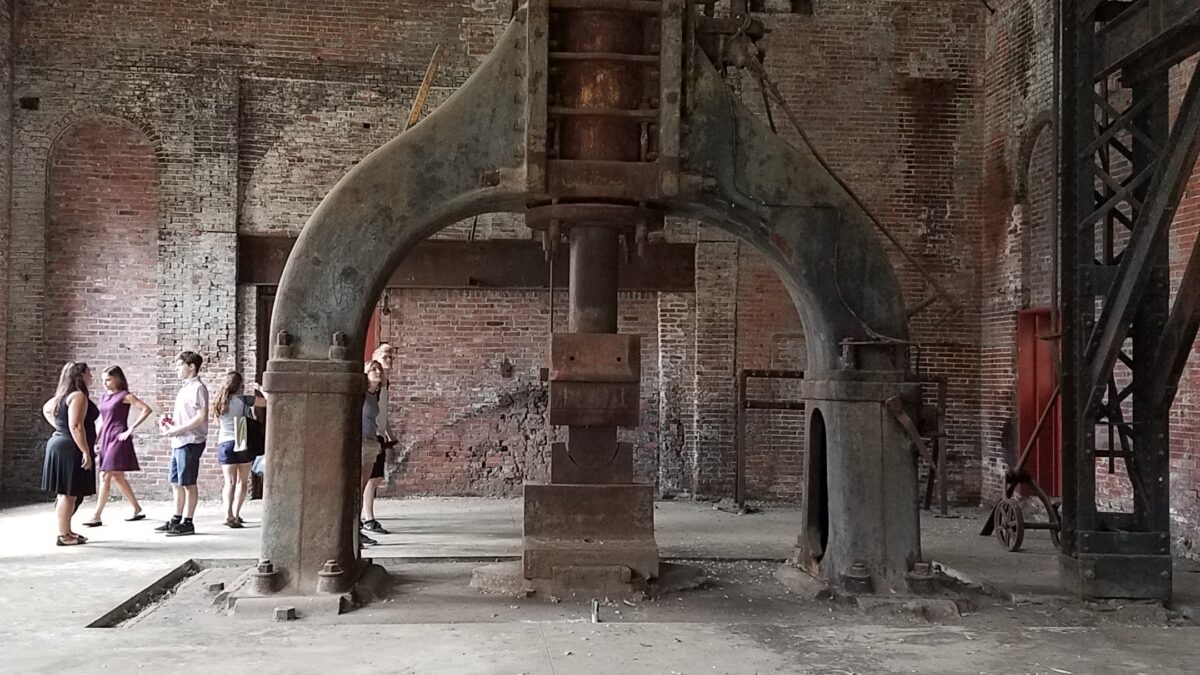 Four teens behind a large metal structure in a large brick building