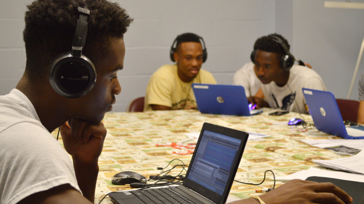 Three youth wearing headphones looking at laptop computers