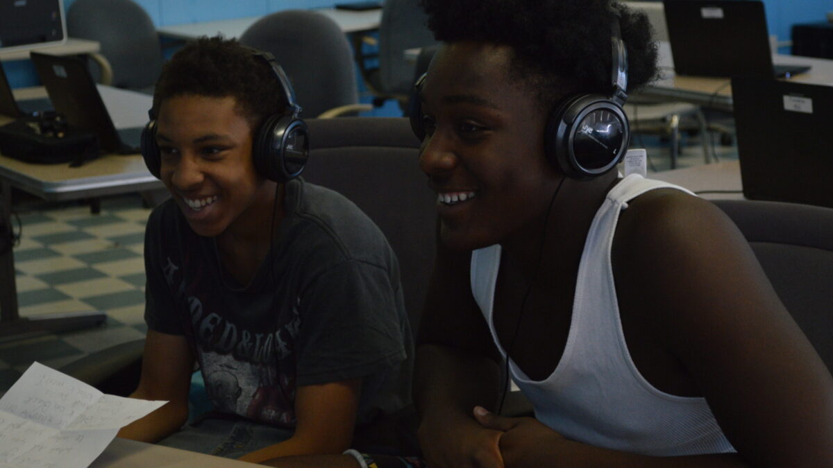 Two teens wearing headphones smiling