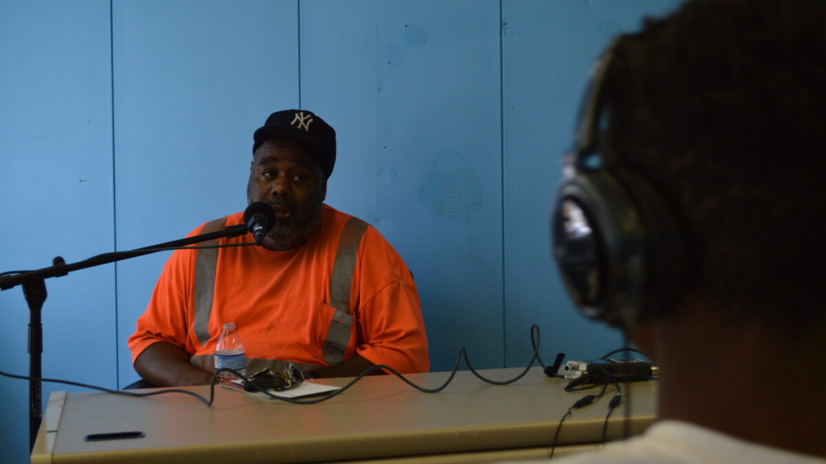 A youth wearing headphones interviewing an adult speaking into a microphone