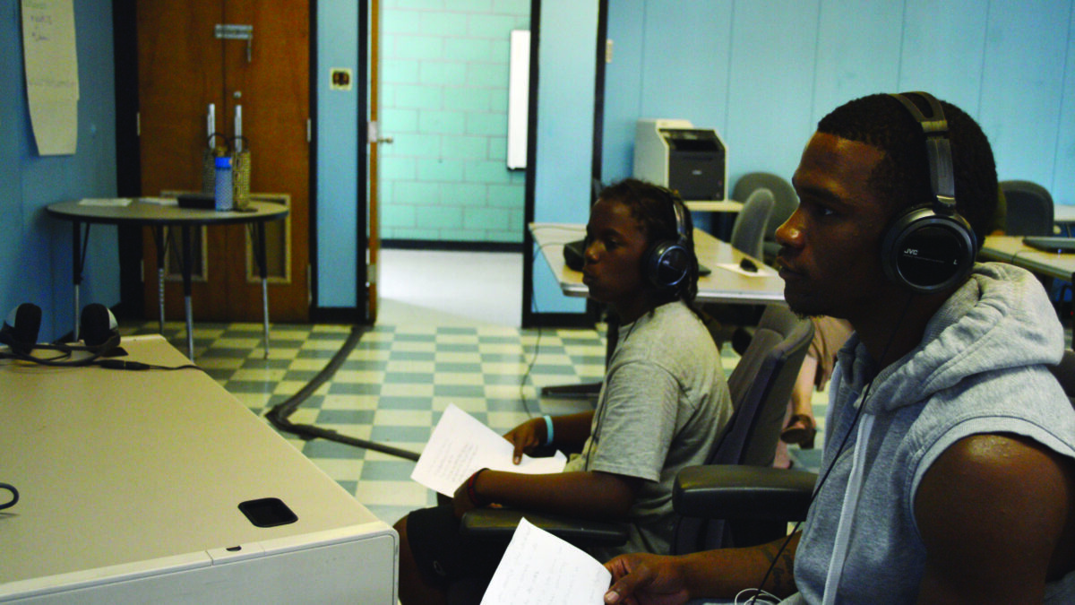Two youth wearing headphones holding pieces of paper