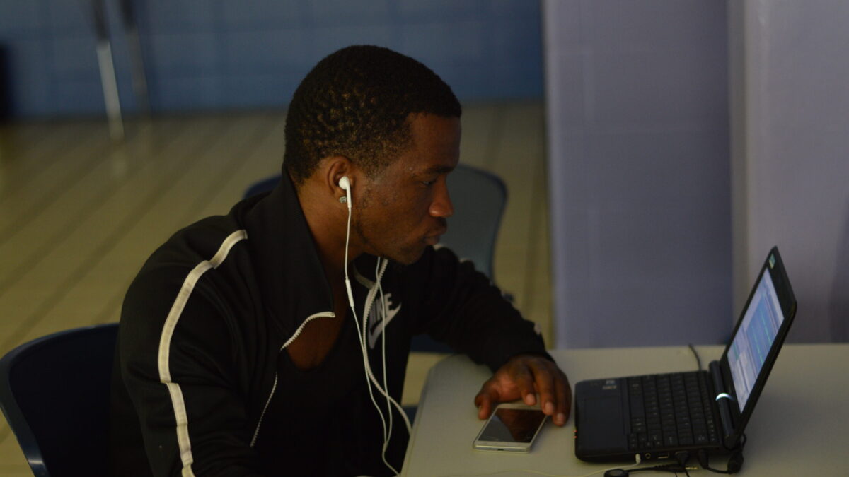 An individual wearing earphones looking at a laptop computer.