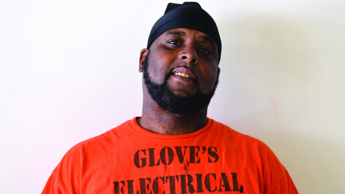 An adult wearing an orange shirt posing in profile