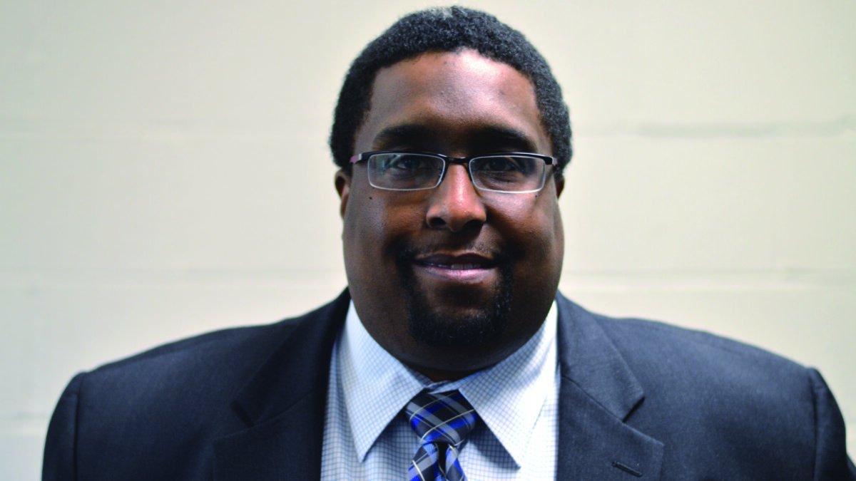 An adult wearing a suit posing in profile