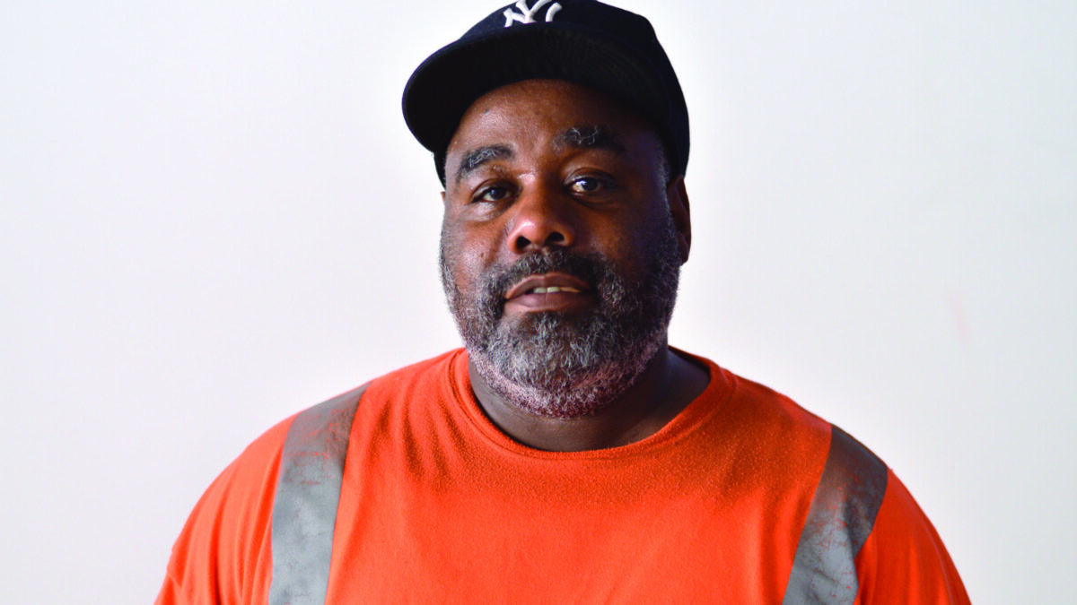 An adult wearing an orange shirt with gray stripes posing in profile