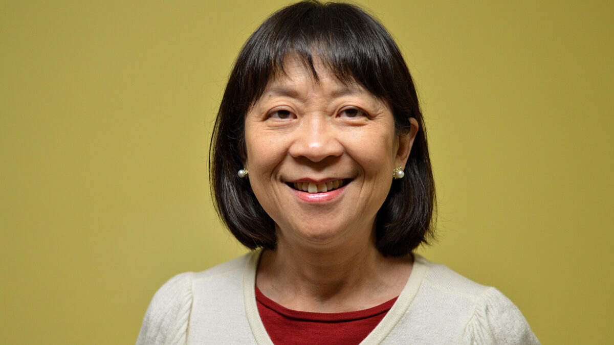An adult wearing a white shirt smiling in profile